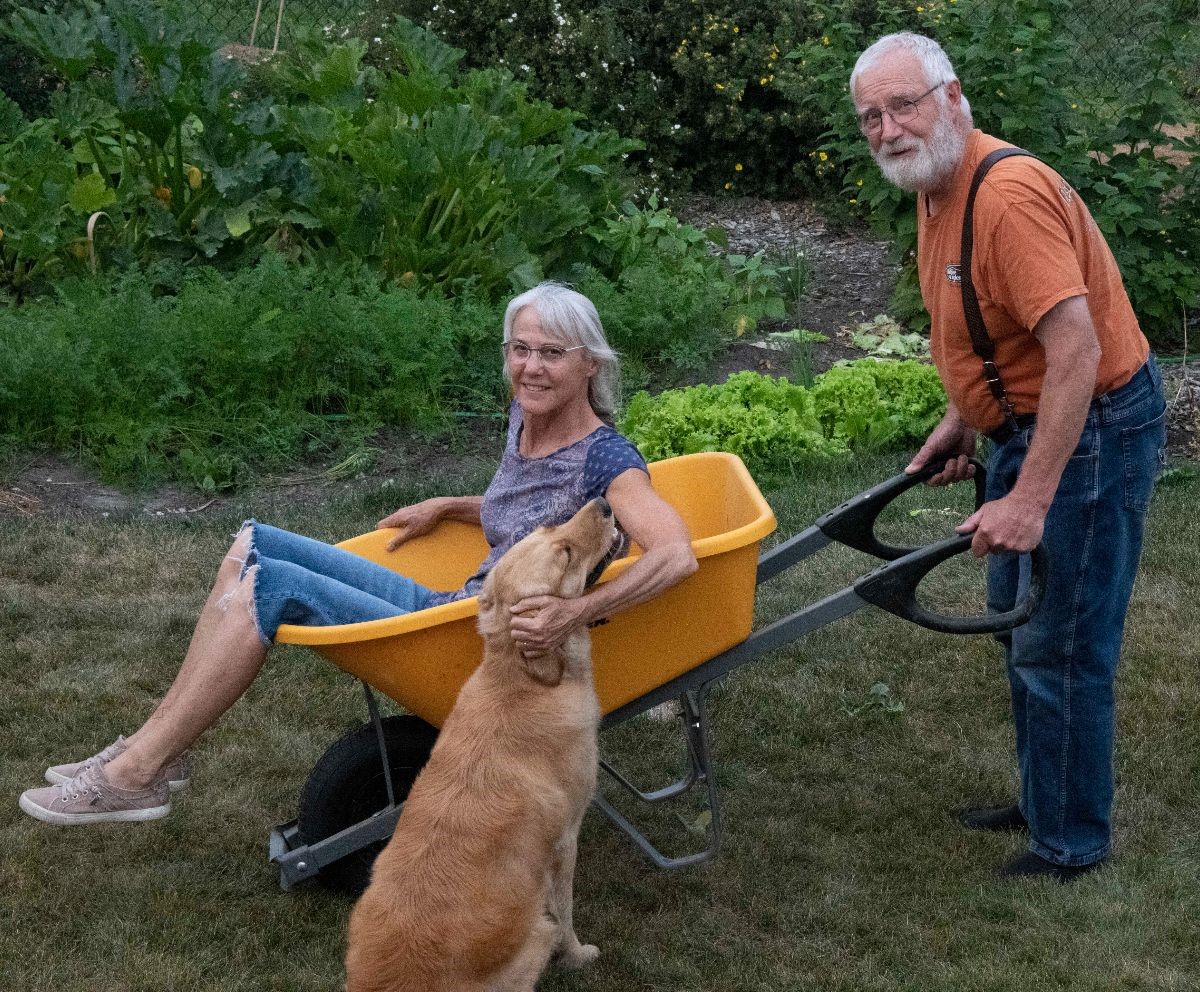 Phil and Karen Rispin with their dog; Karen is in a wheelbarrow, Phil is ready to push her